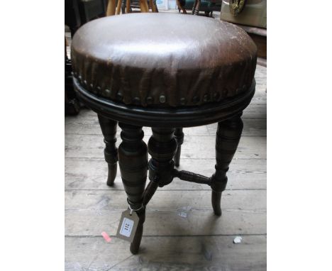 Circular topped stool on 4 splayed turned legs, the studded padded top upholstered in original brown leather