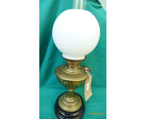 Brass oil lamp on circular ebonised plinth with domed, clouded glass shade