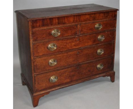 An early 19thC oak and mahogany chest, the over hanging moulded top with a wide mahogany cross banding above two short and th