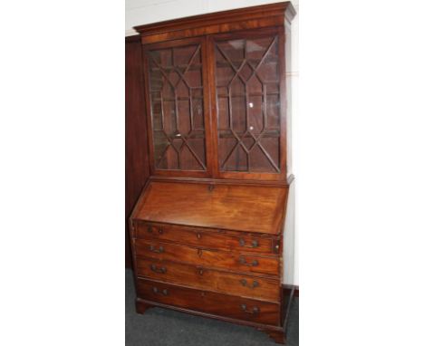 A George III mahogany bureau bookcase, the upper section with an overhanging fixed cornice above a pair of astragal glazed do