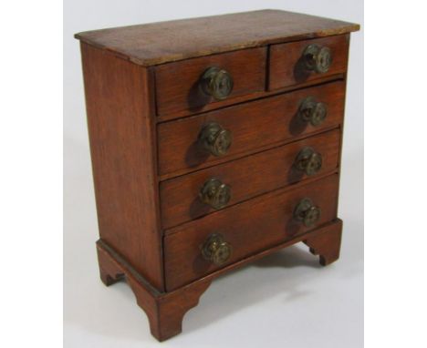 An early 20thC oak miniature chest, of two short and three long drawers, on bracket feet, 28cm high, 25cm wide, 13cm deep. (A