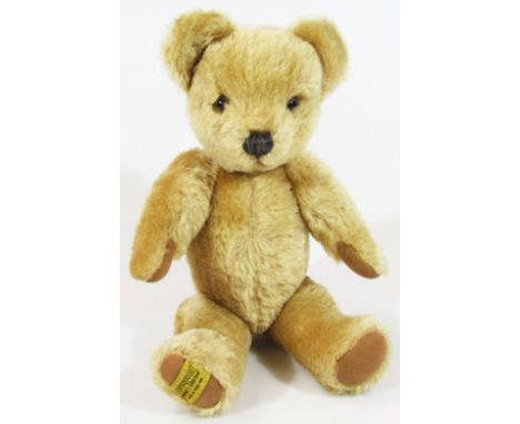 A 20thC Merrythought blonde plush jointed Teddy bear, with glass eyes and velvet finished pads with Ironbridge label to the b