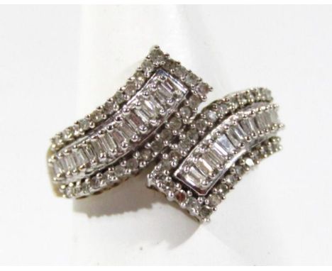 A ladies crossover baguette cut style ring, set with white stones, yellow metal marked 9K, K-L, 4g all in.