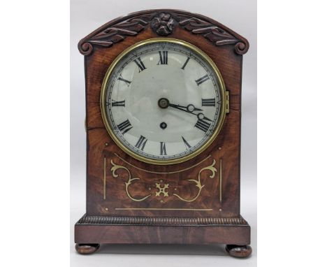 A Regency mahogany bracket clock, the arched top case carved with scrolls, motif to the centre, brass inlaid, ring handles an