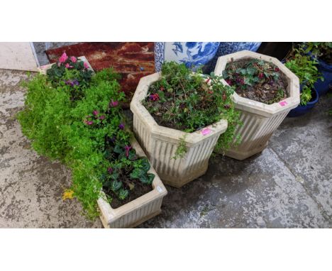 A pair of octagonal garden composite stone planters with vertical fluted design on shaped plinth base, in the Classical style