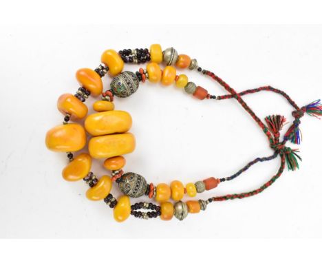 Two Moroccan Berber style pressed amber and white metal, necklaces, one with coral, and enamel to the white metal beads, both
