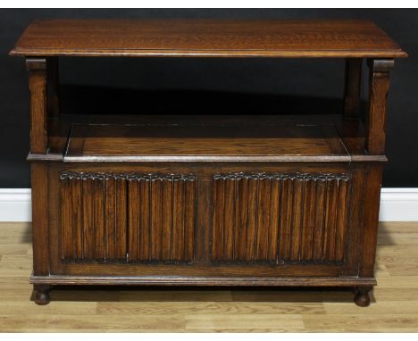 An oak monk's bench, linen-fold back and front panels, hinged seat, 99.5cm high (in bench form), 107cm wide, 48cm deep 