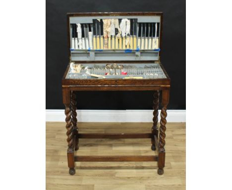 A 1930s canteen table comprising a set of EPNS flatware, some other flatware, cutlery, one silver and enamel teaspoon, hinged