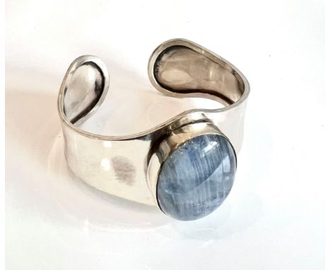 A silver and blue moonstone bangle - the shaped bangle set to the centre with a large oval cabochon moonstone, 33 x 26mm.