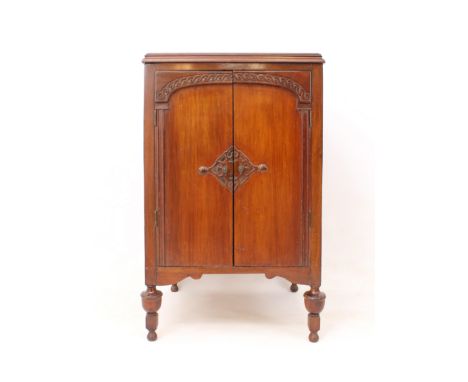 A 1920s-30s mahogany two-door record cabinet - the moulded top over a pair of doors carved with architectural-style arched de