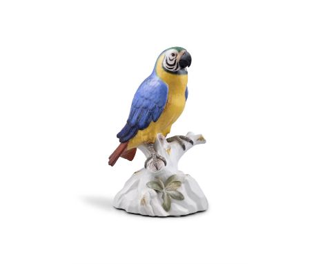 A 19TH CENTURY MEISSEN PAINTED PORCELAIN BLUE AND YELLOW PARROT standing on a tree trunk with foliage, incised model number '