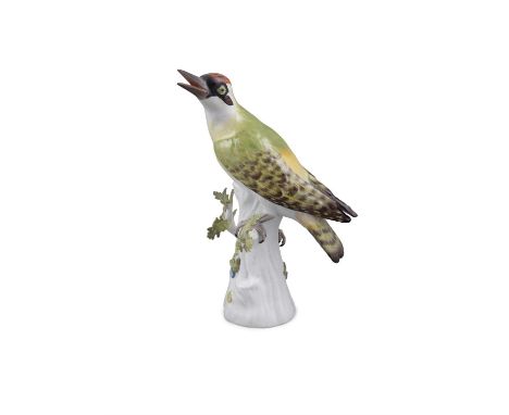 A 20TH CENTURY MEISSEN PAINTED PORCELAIN MODEL OF A GREEN WOODPECKER on a tree stump with leafy boughs, with blue crossed swo