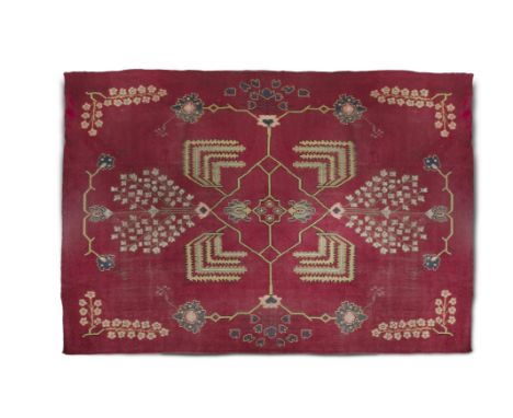 A LARGE ARTS AND CRAFTS RED GROUND WOOL CARPET, probably Donegal, c.1920, unlabelled, of traditional design with central loze