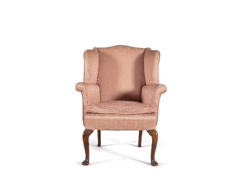 A GEORGE II STYLE UPHOLSTERED WING BACK ARMCHAIR, of compact proportions, covered in damask cloth and raised on carved walnut
