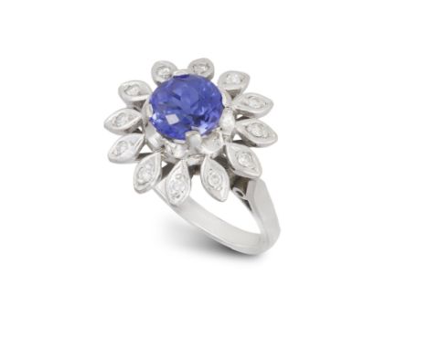 A TANZANITE AND DIAMOND DRESS RING, designed as a flowerhead with a central circular-cut tanzanite within a surround of singl