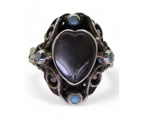 AN ARTS & CRAFTS RING made in sterling silver, set with a leaf carved heart shape moonstone, and four turquoise glass gems (o