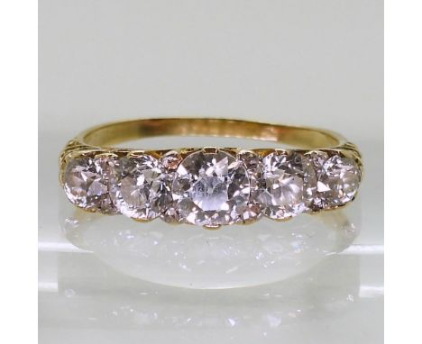 A FIVE STONE RING in classic yellow metal scroll mount, set with five old cut diamonds with a combined diamond total of 1.10c