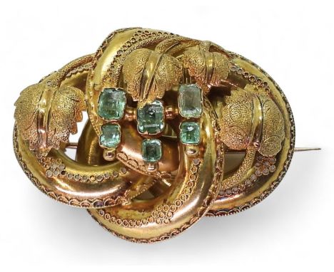 A VICTORIAN BROOCH&nbsp; the knot form with applied wire work details, is made in yellow metal and set with six step cut emer