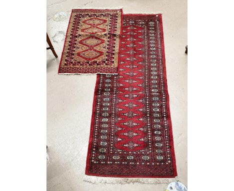 A modern red ground hand knotted Pakistan Bokhara runner and similar smaller rug 