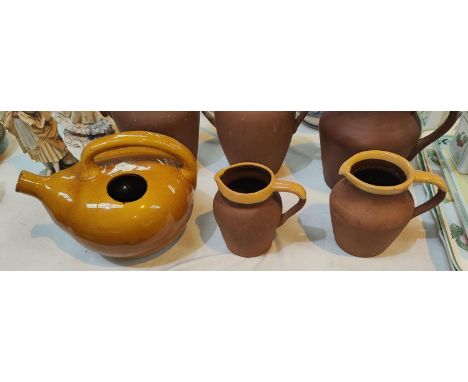 Two vintage terracotta milk jugs with yellow rims and an unusual wine pot in yellow glaze 