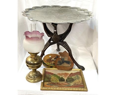 A Middle Eastern folding table with lobbed top etched and a tripod wooden leg set; oil paintings and oil lamp with frosted gl