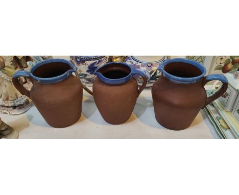 Three vintage terracotta milk jugs with blue rims 