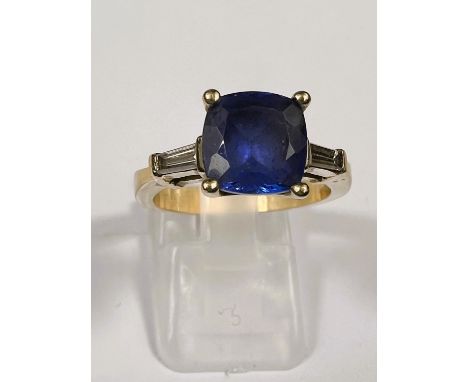 A modern ladies dress ring set square cut tanzanite with diamond baton to each shoulder, the yellow metal shank stamped '14k'