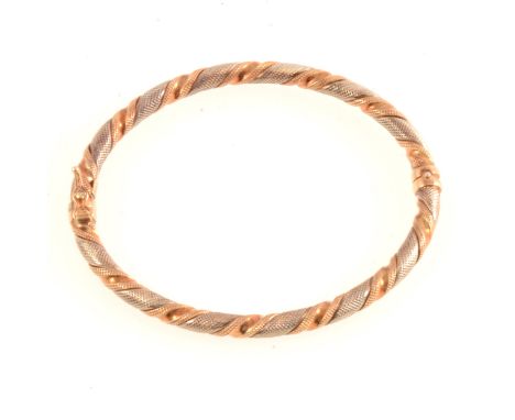 A 9 carat yellow and white gold half hinged bangle, 4.5mm wide round section, milled twisted design, Sheffield import mark fo