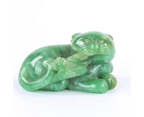A Chinese carved jade figure, 18th / 19th century, in mottled green jade with a few light brown inclusions, depicting a recum