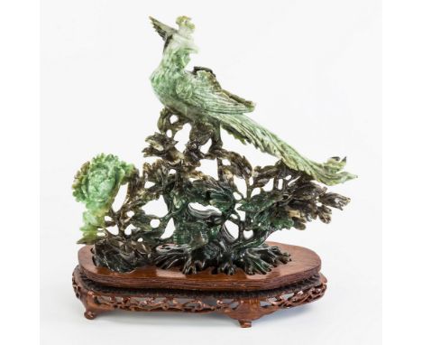 A Chinese light green, dark green and brown mottled jade figure, late 20th century, modelled as a Ho-Ho bird atop a flowering