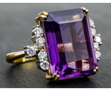 A yellow gold, amethyst and diamond ring, the large emerald cut amethyst set with five brilliant cut diamonds to each shoulde