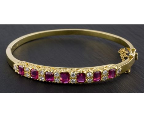 An 18ct yellow gold, ruby and diamond bangle, maker TOD, London 1970, in the Victorian style, the seven graduated emerald cut