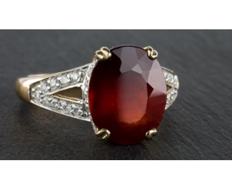 A 9ct yellow gold, red stone and diamond ring, the central oval cut stone of deep red colour (possibly a spinel), on a diamon