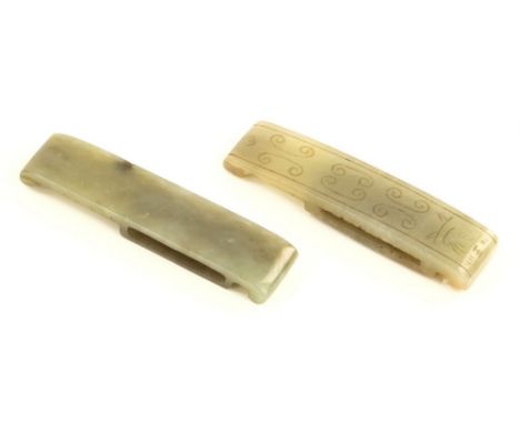 Two antique Chinese carved jade sword slides, possibly Han Dynasty (206BC-220AD), one celadon green, engraved with c-scrolls 