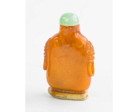A Chinese egg yolk amber snuff bottle, 18th / 19th century, rounded straight sided form, relief carved taotie mask and ring h