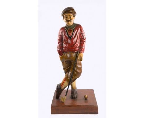 An impressive painted wooden advertising figure, carved as a gentleman golfer with beige peaked cap, red V neck jumper, polka