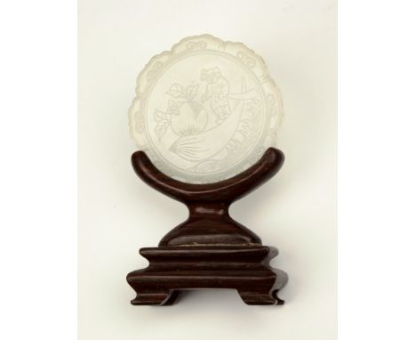 A Chinese carved white jade pendant plaque, probably 19th century, lotus form with engraved circular reserve of a figure tran