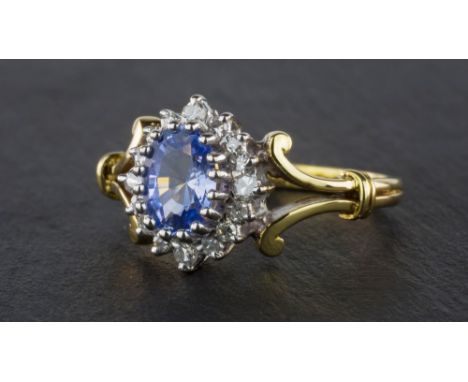 An 18ct yellow gold, Tanzanite & diamond cluster ring, the oval cut pale Tanzanite within a border of brilliant cut diamonds,