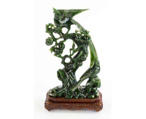 A Chinese dark spinach green jade figure, late 20th century, depicting a Ho-Ho bird in the branches of a peach tree, a second