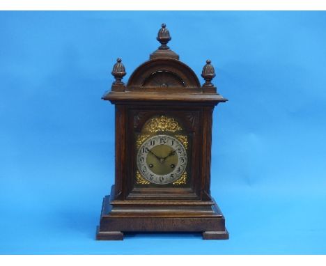 An early 20thC oak cased Mantel Clock, of arched form with finials and pilasters, the brass dial with silvered chapter ring, 