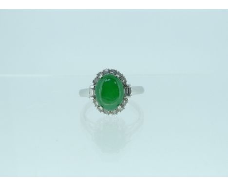 A attractive jade and diamond Ring, the oval cabochon jade with six small diamonds above and below and a baguette diamond on 