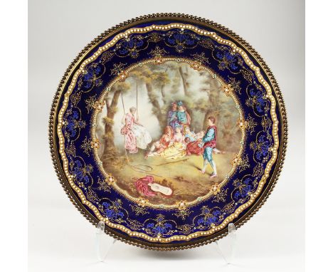 A VERY GOOD FRENCH ENAMEL CIRCULAR DISH, painted with a scene, lady on a swing with children. 5ins diameter.
