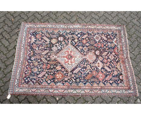 A PERSIAN QASHQAI RUG, early 20th century, dark blue ground with a central diamond shaped panel. 7ft 5ins x 4ft 10ins.