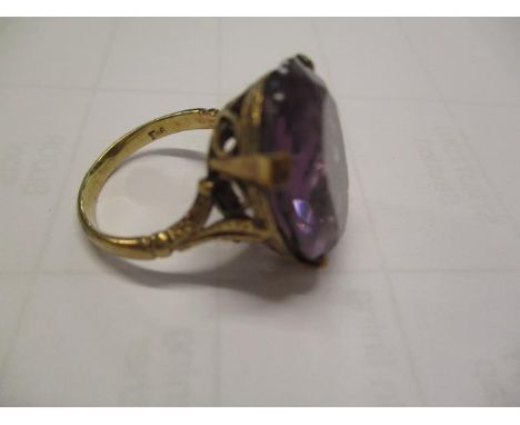 A gold coloured metal ring set with an amethyst in an engraved mount, 6.6g 