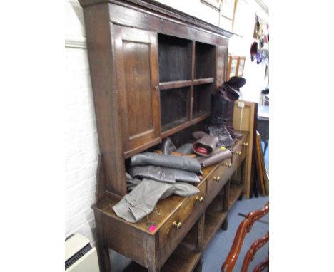 A George III oak dresser, having two shelves flanked by a pair of doors, over three inline drawers and a shelf, 72h x 71w x16