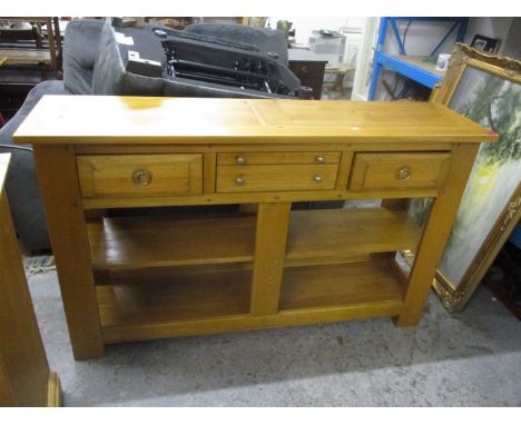 A modern light oak dresser base, with central drawers flanked by fielded drawers and shelf below on squared legs, 34 1/2 h x 