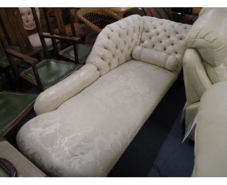 An Edwardian mahogany and cream, floral upholstered chaise longue, with a button back, and bolster cushion, on turned legs an