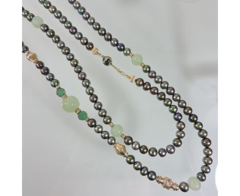 A JKa pearl and jade coloured long single strand bead necklace, set with thirteen carved jade coloured beads, with an 18 cara