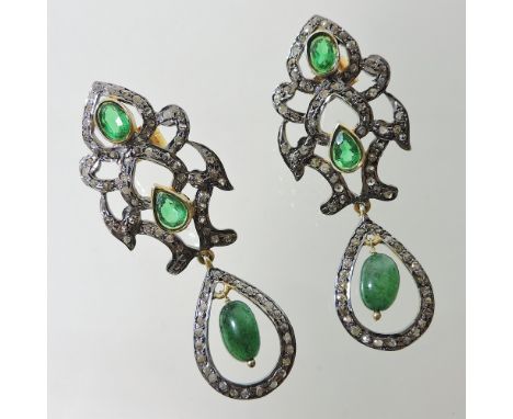 A pair of unmarked emerald and diamond pendant earrings, each collet set, within a scrolled diamond set surround, 5cm drop 