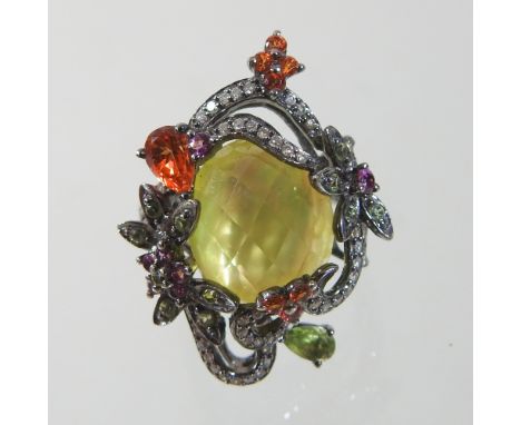 A modern 14 carat gold multi gem set designer ring, the central faceted stone, within a flowing line set diamond surround, si